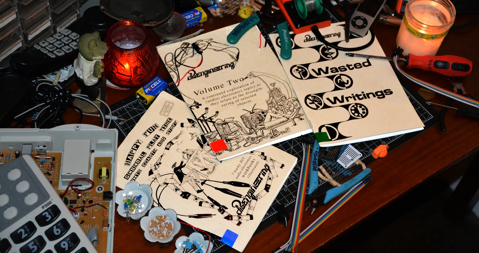 Three disengineering zines on a workbench with tools and components