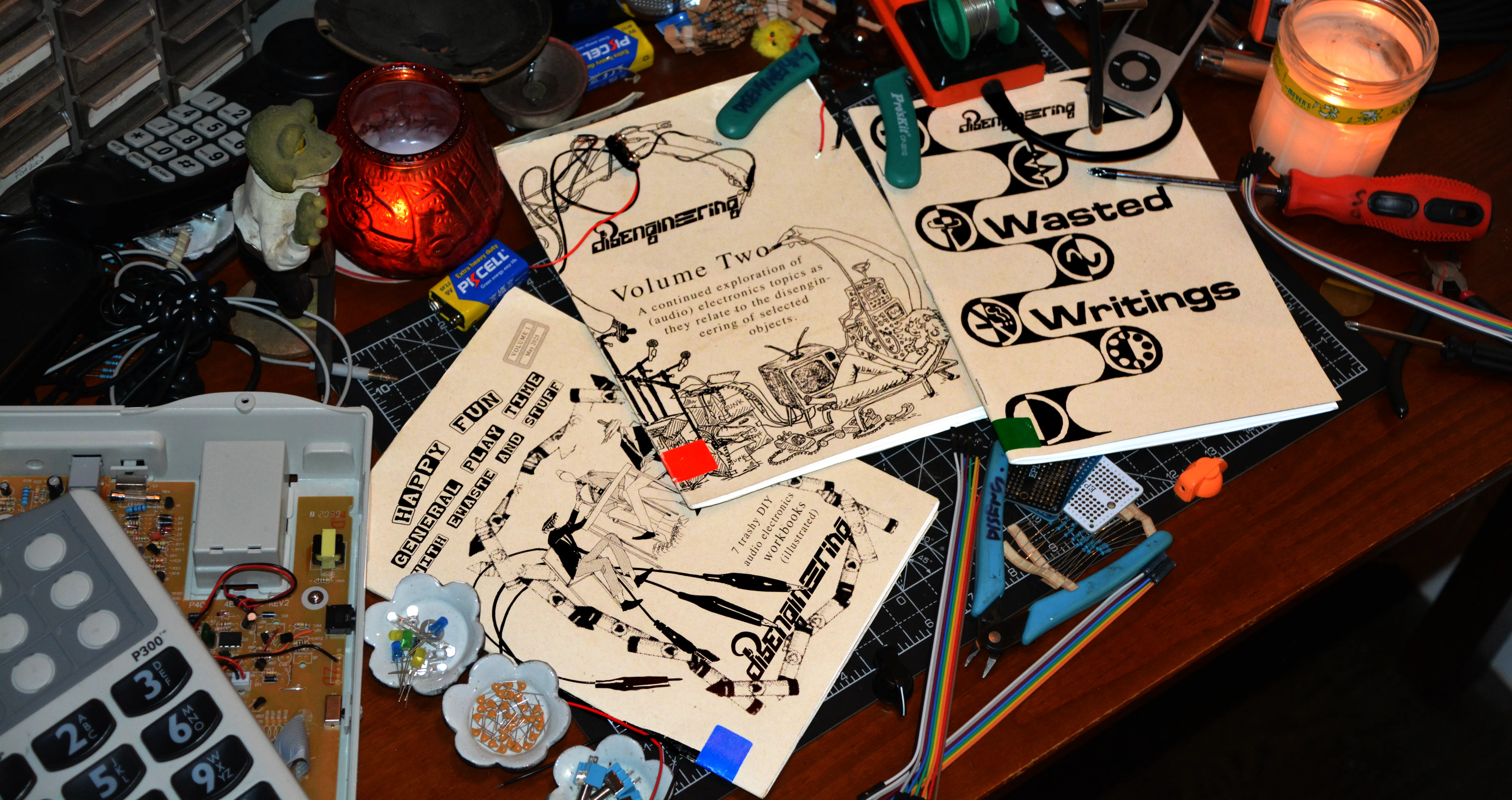 Three disengineering zines on a workbench with tools and components